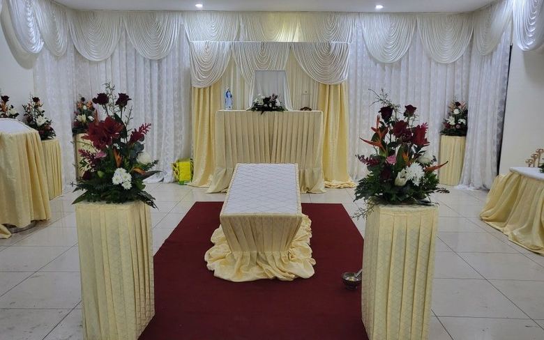 Salle de recueillement aménagée : tentures claires, compositions florales et allée centrale